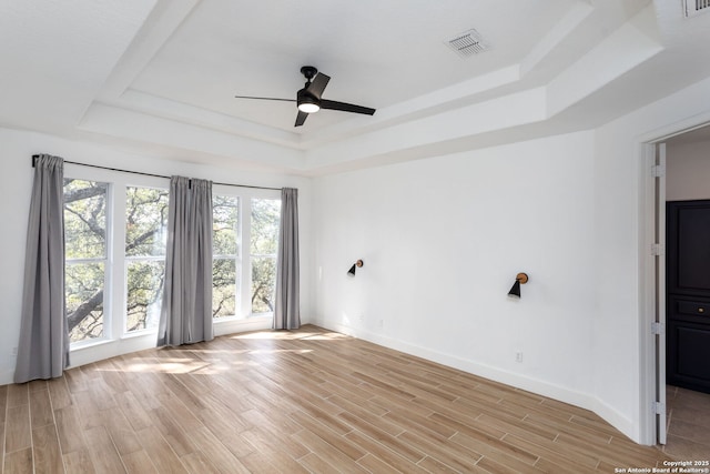 spare room with a raised ceiling, ceiling fan, and light hardwood / wood-style floors