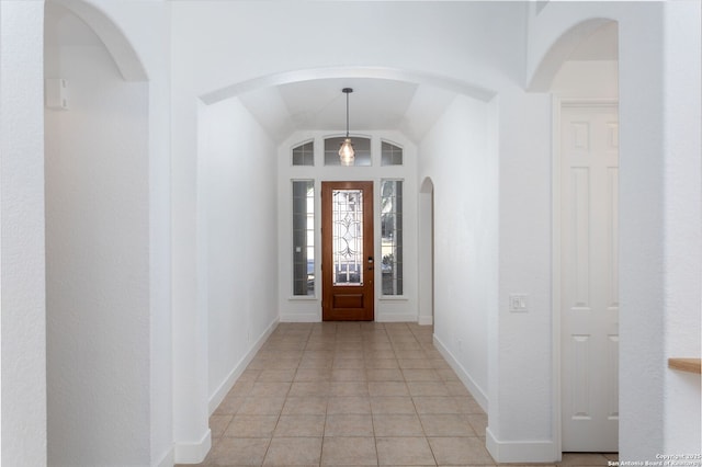 entryway with light tile patterned flooring and vaulted ceiling