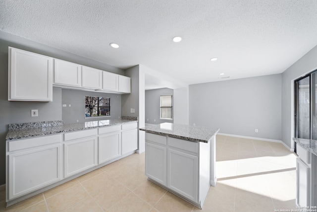 kitchen with light stone countertops, white cabinets, and light tile patterned floors