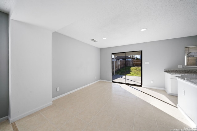 unfurnished living room with light tile patterned floors and a textured ceiling