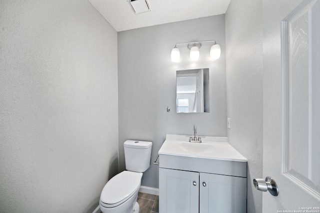 bathroom featuring vanity, a textured ceiling, and toilet