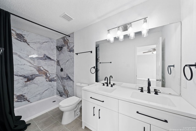 bathroom with vanity, a textured ceiling, ceiling fan, tiled shower, and toilet