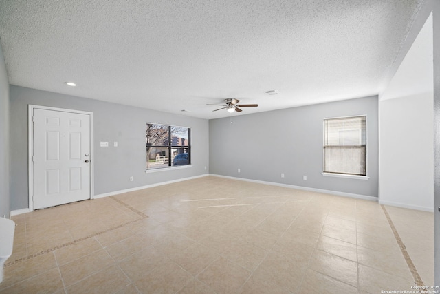 spare room featuring ceiling fan, light tile patterned floors, and a textured ceiling