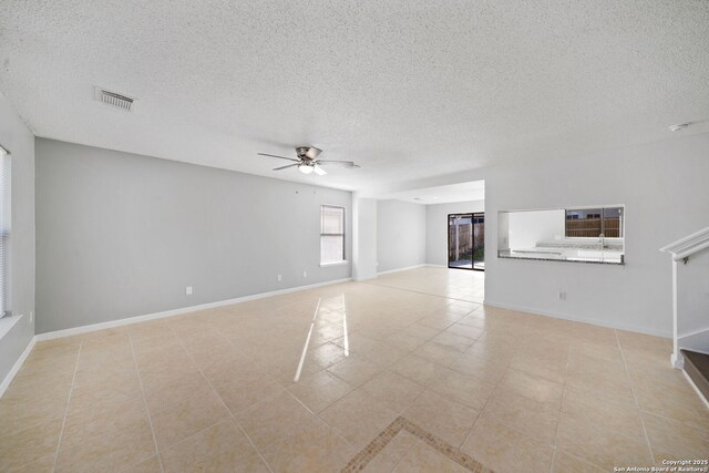 unfurnished living room with ceiling fan, light tile patterned floors, and a textured ceiling