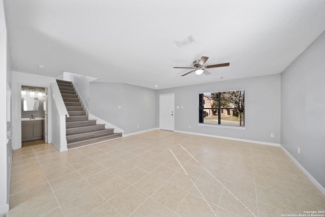 unfurnished living room featuring a textured ceiling, ceiling fan, light tile patterned floors, and sink