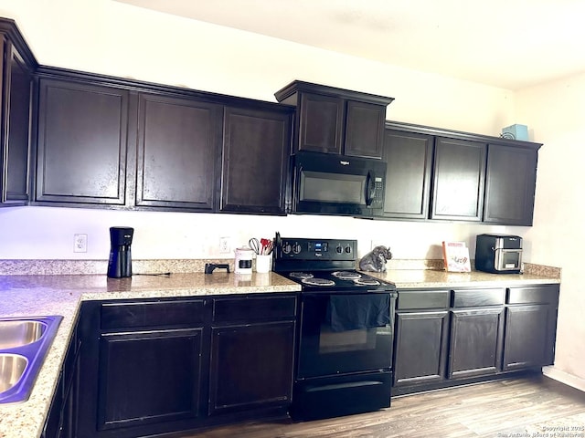 kitchen with sink, black appliances, and light hardwood / wood-style floors