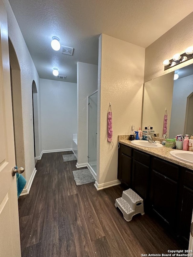 bathroom with vanity, independent shower and bath, a textured ceiling, and hardwood / wood-style flooring