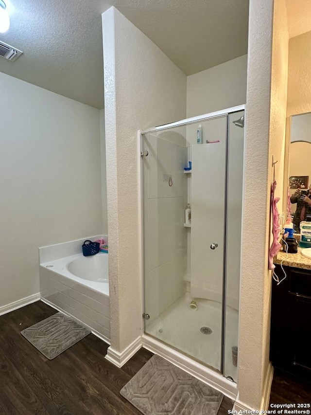 bathroom featuring wood-type flooring, a textured ceiling, and shower with separate bathtub