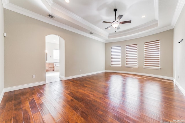 spare room featuring dark wood-type flooring, a tray ceiling, ceiling fan, and crown molding