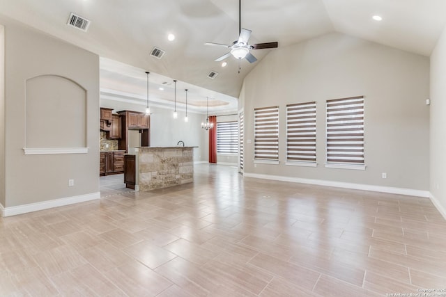 unfurnished living room featuring ceiling fan with notable chandelier and vaulted ceiling