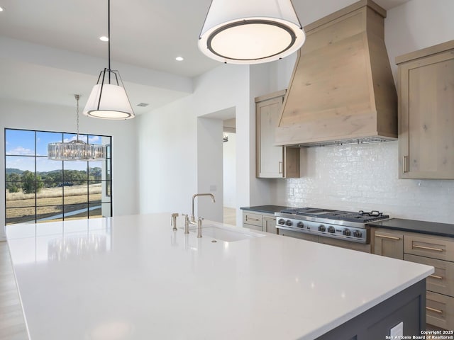 kitchen with custom exhaust hood, a center island with sink, sink, hanging light fixtures, and decorative backsplash