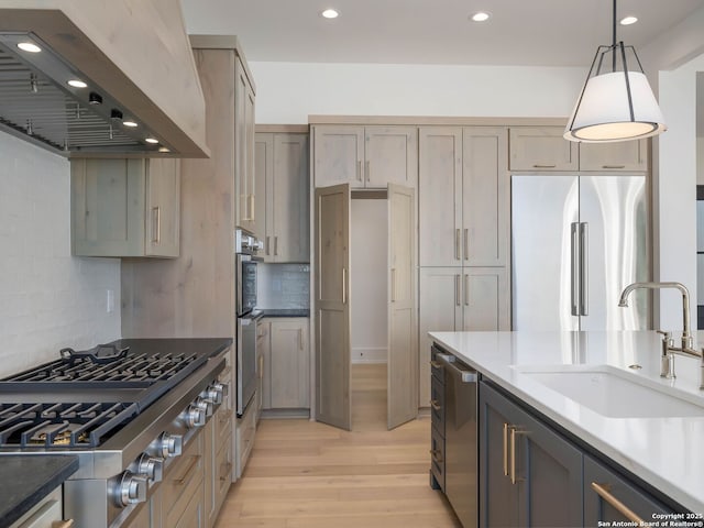 kitchen featuring premium range hood, hanging light fixtures, sink, appliances with stainless steel finishes, and tasteful backsplash