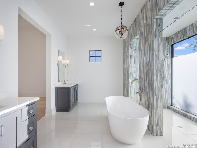 bathroom with a bathing tub, vanity, tile patterned flooring, and a chandelier