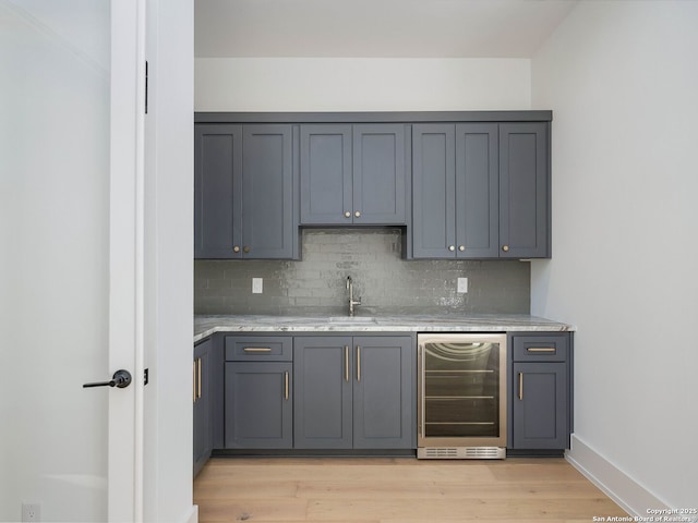 bar featuring decorative backsplash, gray cabinets, wine cooler, and light hardwood / wood-style floors