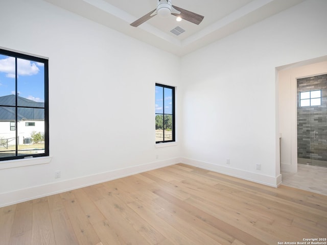 empty room with a high ceiling, light wood-type flooring, and ceiling fan