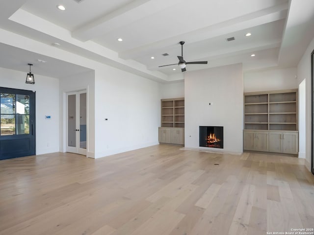 unfurnished living room with ceiling fan, a raised ceiling, beamed ceiling, light hardwood / wood-style floors, and a fireplace