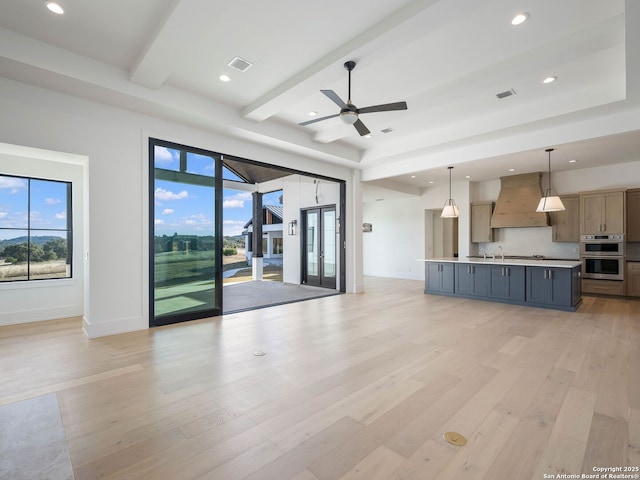 unfurnished living room with beamed ceiling, light hardwood / wood-style flooring, ceiling fan, and sink