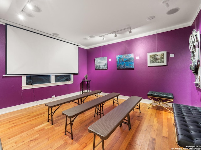 cinema room with rail lighting, crown molding, and hardwood / wood-style floors