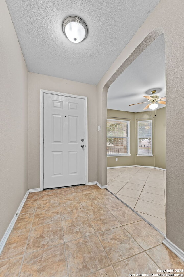 entrance foyer with a textured ceiling, ceiling fan, and light tile patterned flooring