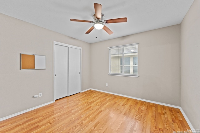 unfurnished bedroom featuring a closet, light hardwood / wood-style floors, and ceiling fan