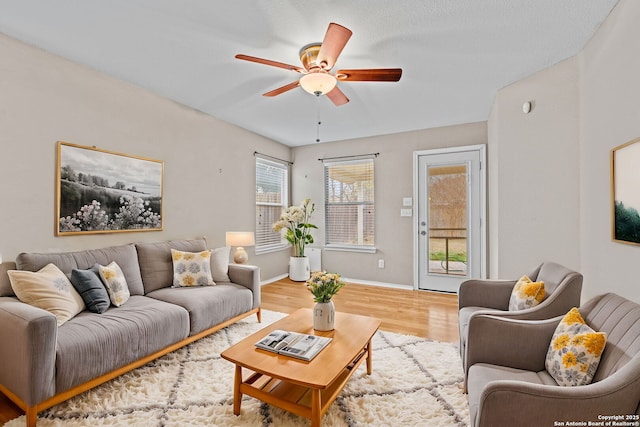 living room featuring ceiling fan, wood-type flooring, and a wealth of natural light