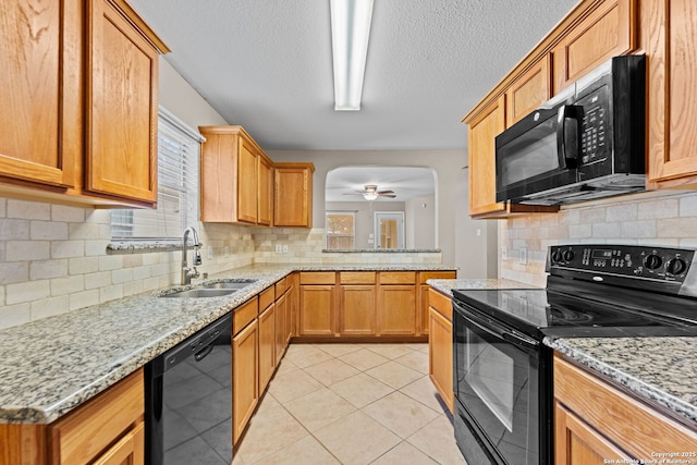 kitchen with light stone counters, ceiling fan, sink, black appliances, and light tile patterned floors