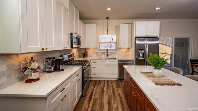 kitchen with white cabinets, pendant lighting, stainless steel appliances, and sink