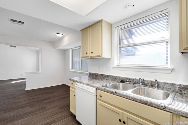 kitchen with dark wood-type flooring, cream cabinets, white dishwasher, sink, and a healthy amount of sunlight