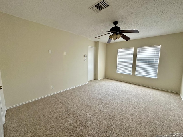 empty room with ceiling fan, light colored carpet, and a textured ceiling