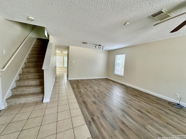 unfurnished living room with ceiling fan, light tile patterned floors, a healthy amount of sunlight, and track lighting