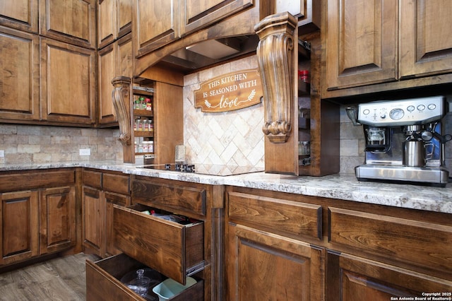 kitchen with backsplash, light stone countertops, black electric stovetop, and dark hardwood / wood-style floors