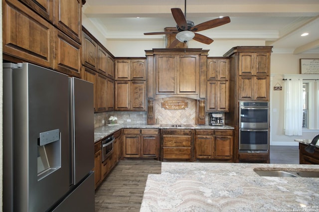 kitchen featuring sink, light stone counters, dark hardwood / wood-style floors, backsplash, and appliances with stainless steel finishes