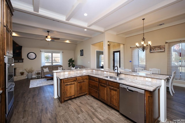 kitchen with dishwasher, ceiling fan with notable chandelier, sink, beamed ceiling, and decorative light fixtures