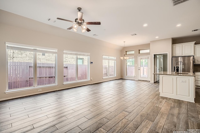 unfurnished living room featuring plenty of natural light and ceiling fan with notable chandelier