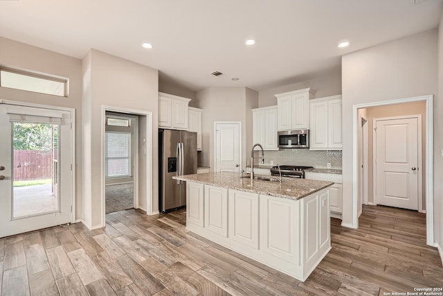 kitchen featuring light stone countertops, sink, an island with sink, white cabinets, and appliances with stainless steel finishes