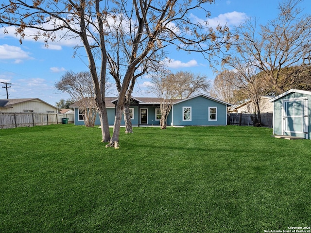 rear view of property with a yard and a storage unit