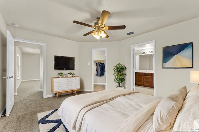 bedroom featuring light carpet, ceiling fan, a spacious closet, connected bathroom, and a closet