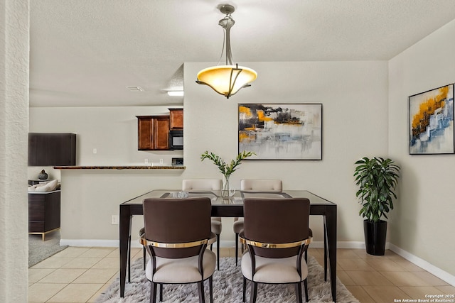 dining area featuring light tile patterned floors and a textured ceiling