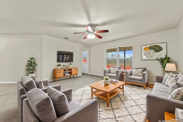 living room with light carpet, ceiling fan, and a textured ceiling