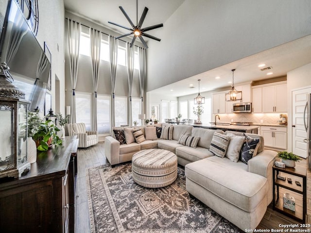 living room featuring ceiling fan, sink, dark hardwood / wood-style flooring, and a towering ceiling