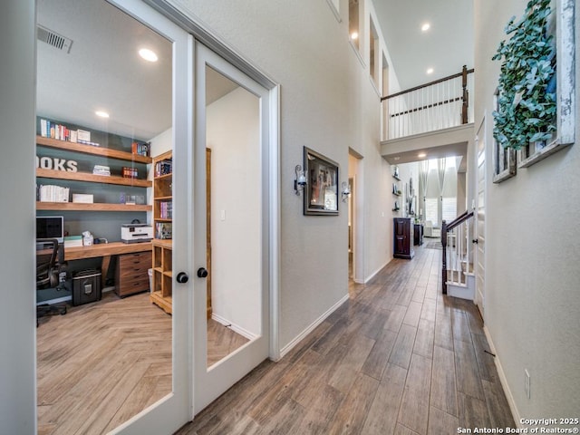 hall featuring a high ceiling, wood-type flooring, and french doors