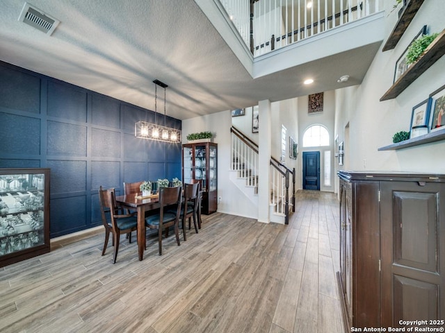 dining area with a towering ceiling, a chandelier, and a textured ceiling