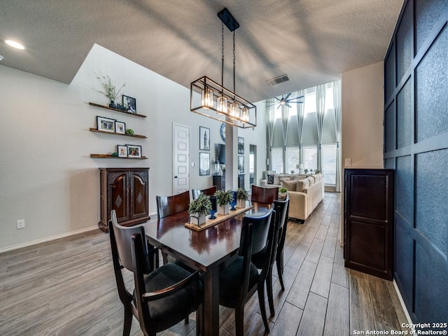 dining area with ceiling fan, a high ceiling, and a textured ceiling