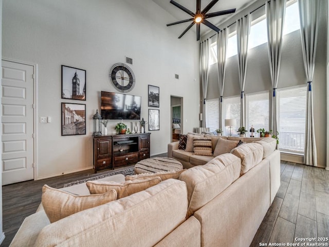 living room with a healthy amount of sunlight, a high ceiling, ceiling fan, and dark hardwood / wood-style flooring