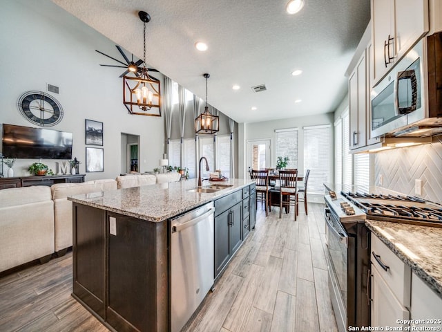 kitchen featuring backsplash, white cabinetry, hanging light fixtures, and appliances with stainless steel finishes