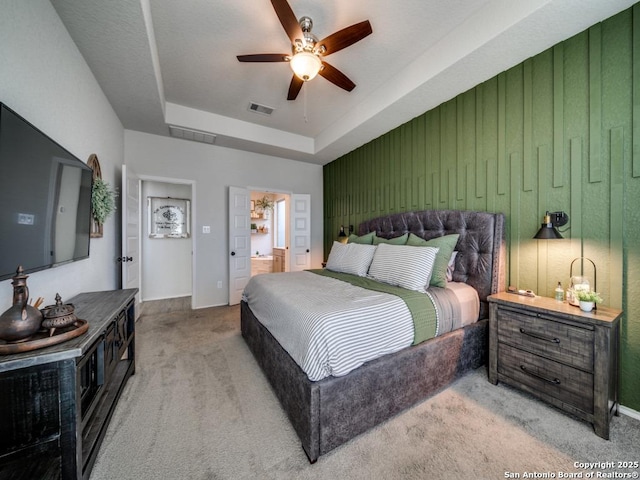 carpeted bedroom with ceiling fan and a tray ceiling