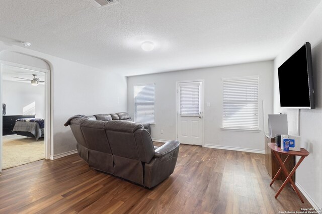 living room with a textured ceiling, dark hardwood / wood-style flooring, and ceiling fan