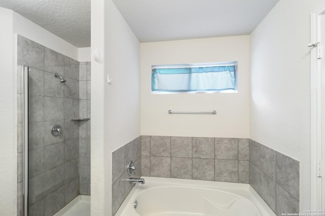 bathroom with a textured ceiling and shower with separate bathtub