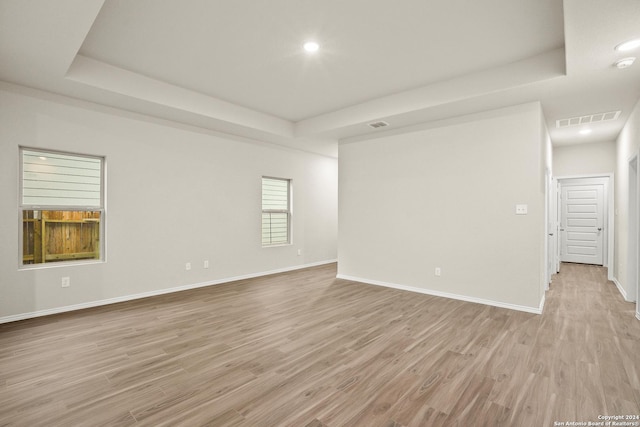 spare room featuring a raised ceiling and light wood-type flooring