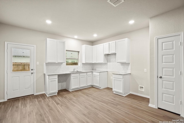 kitchen with white cabinets, light stone countertops, light hardwood / wood-style flooring, and sink